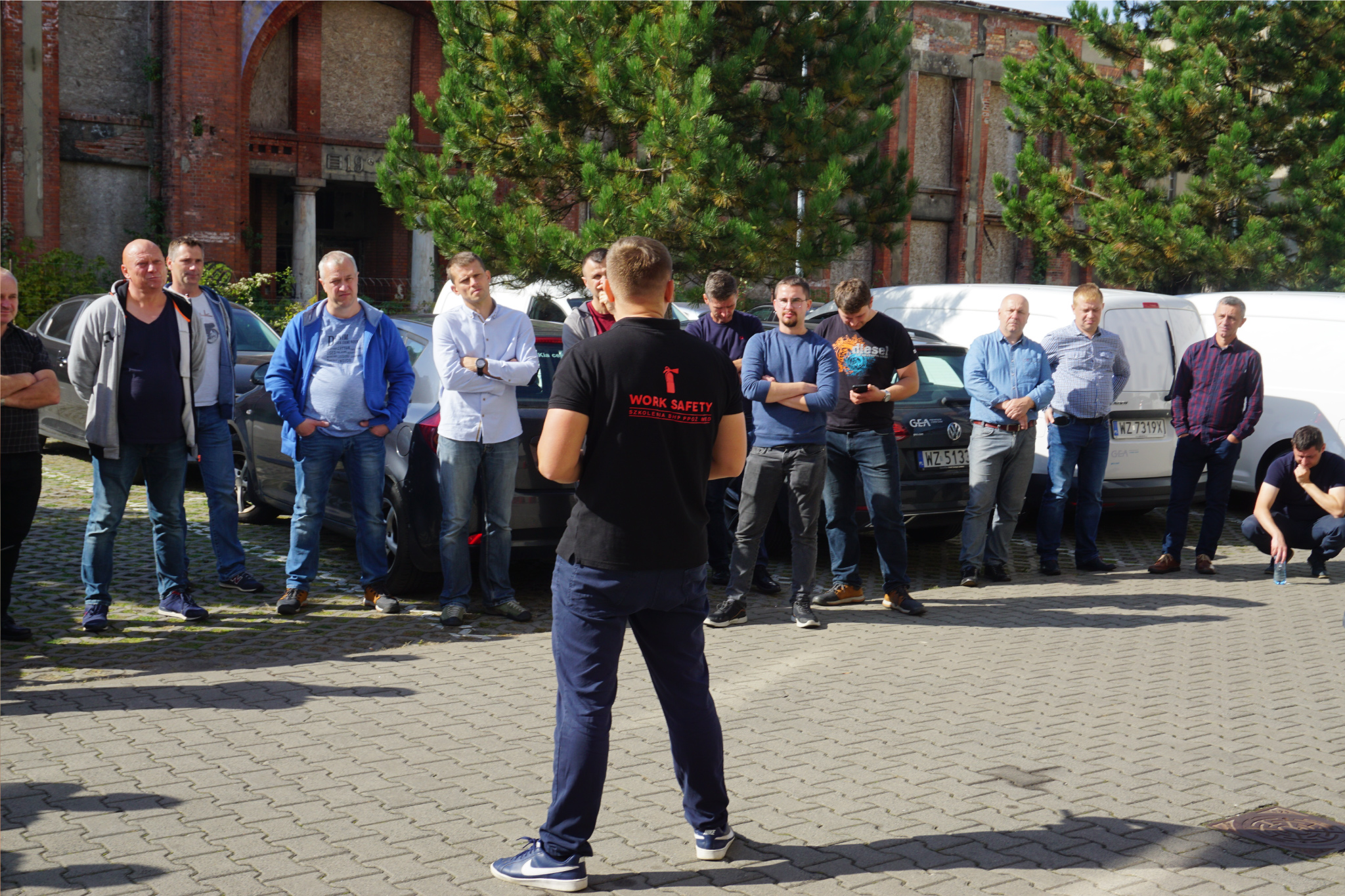 Instruktor Work Safety prowadzi szkolenie BHP na zewnątrz dla grupy pracowników stojących na placu
