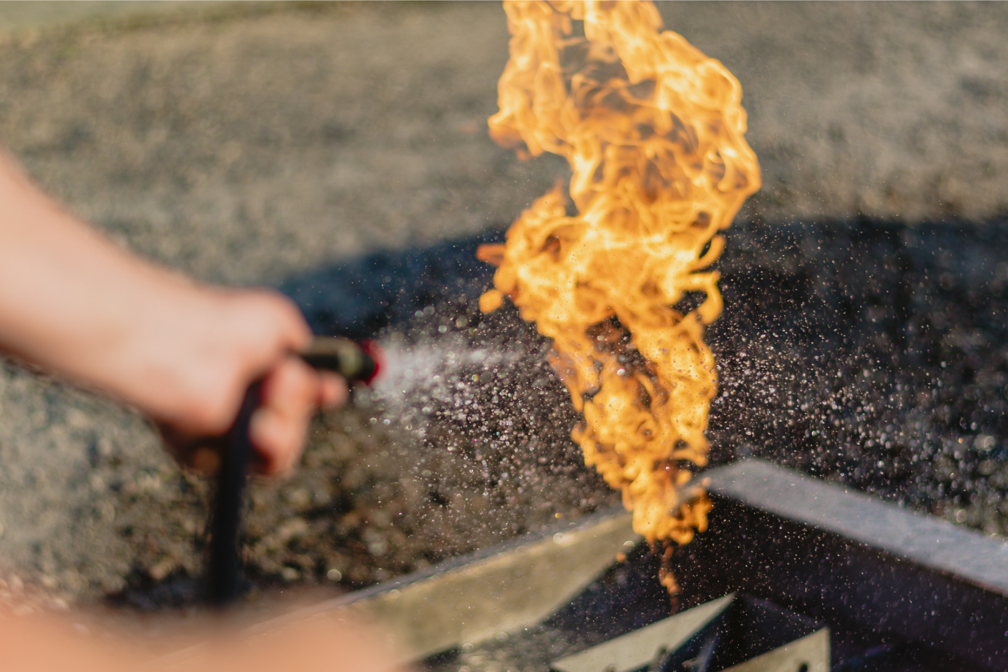Uczestnik szkolenia gasi płomień za pomocą gaśnicy podczas praktycznych ćwiczeń PPOŻ na świeżym powietrzu